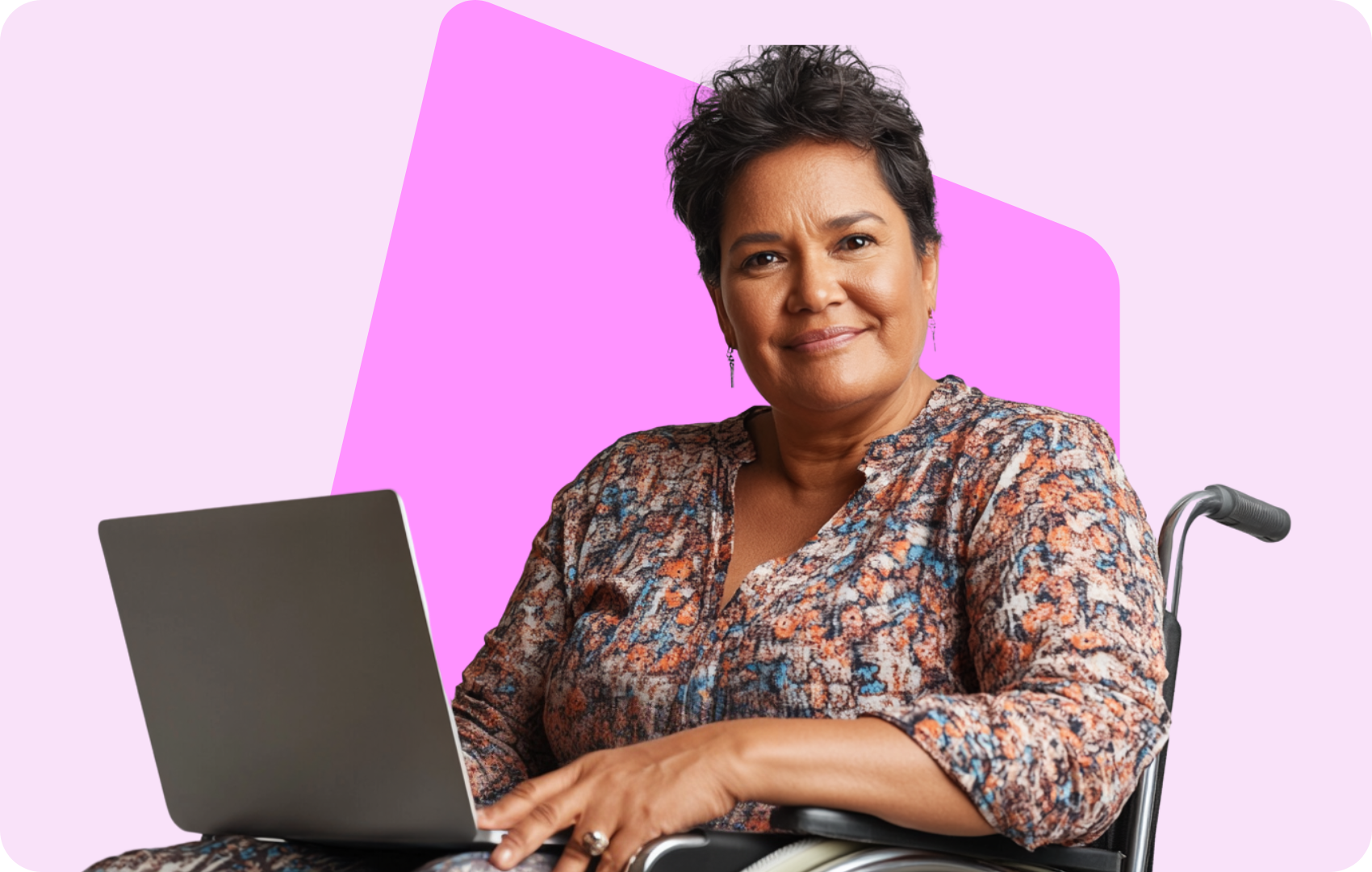 Woman smiling at a desk with a laptop, sitting in front of a pink and purple abstract background.